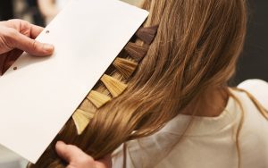 Mulher no salão tendo uma mecha de cabelo com sua cor graduada pela cabeleireira