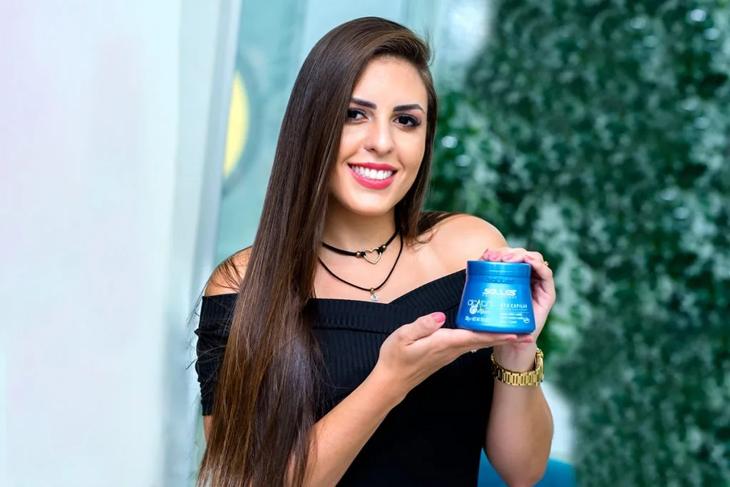 Modelo com cabelos tratados e em foco apresentando produto capilar para a câmera