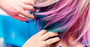 Cabelo colorido em foco sendo pintado por cabeleireira